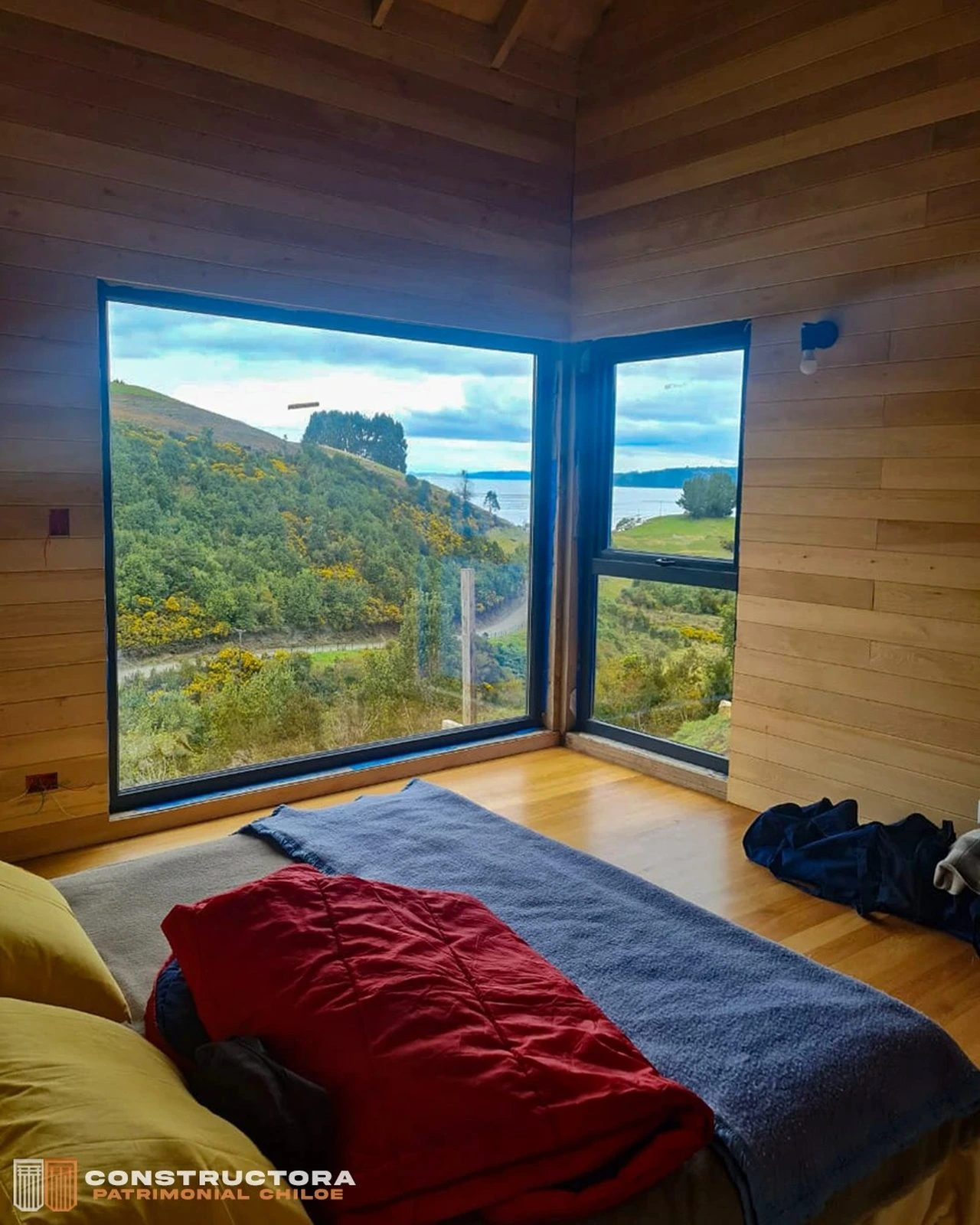 Dormitorio de Casa Los Capurro con ventanal esquinero y vista al mar de Chiloé